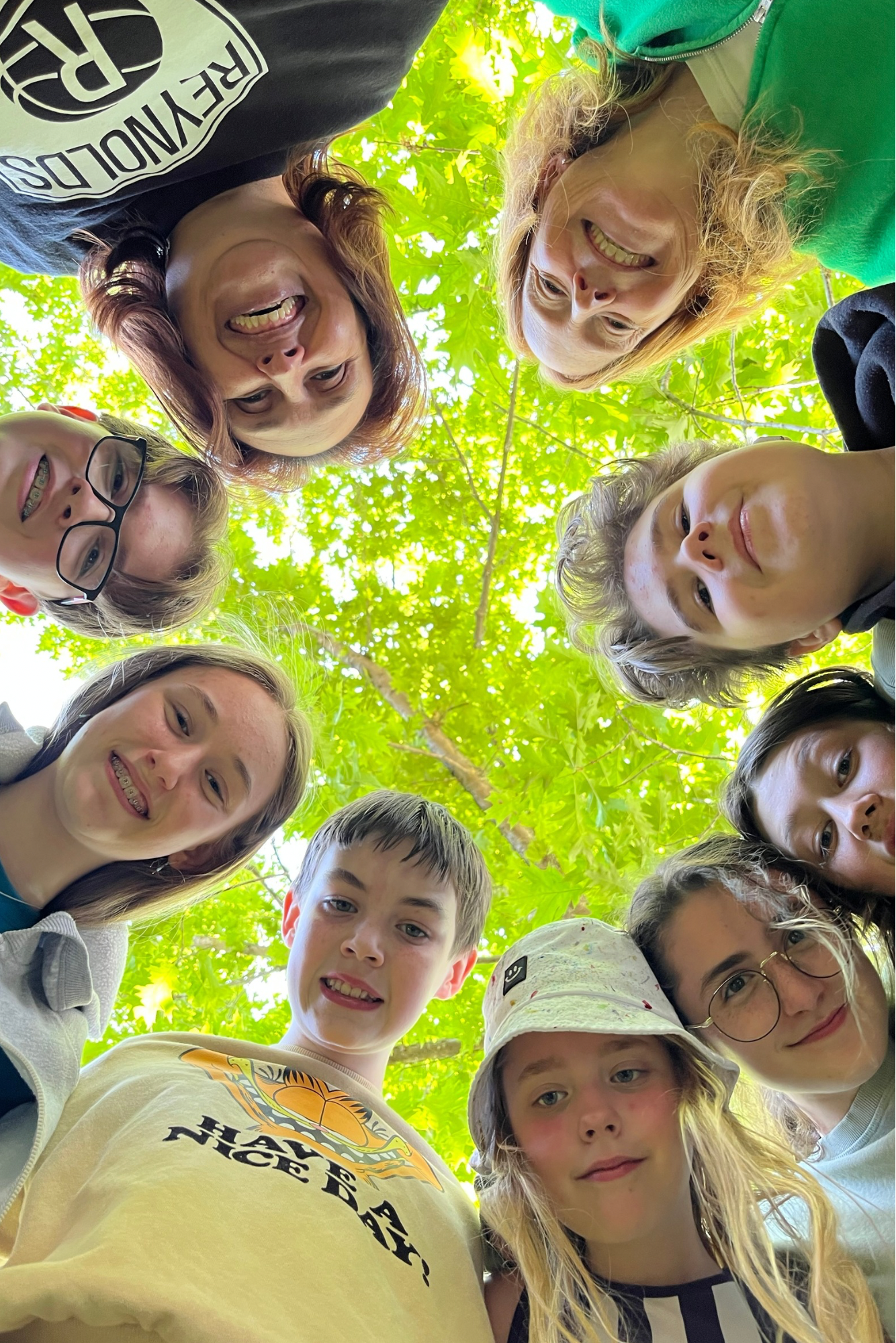 Samll group of students and their teacher looking at the camera underneath a beautiful tree