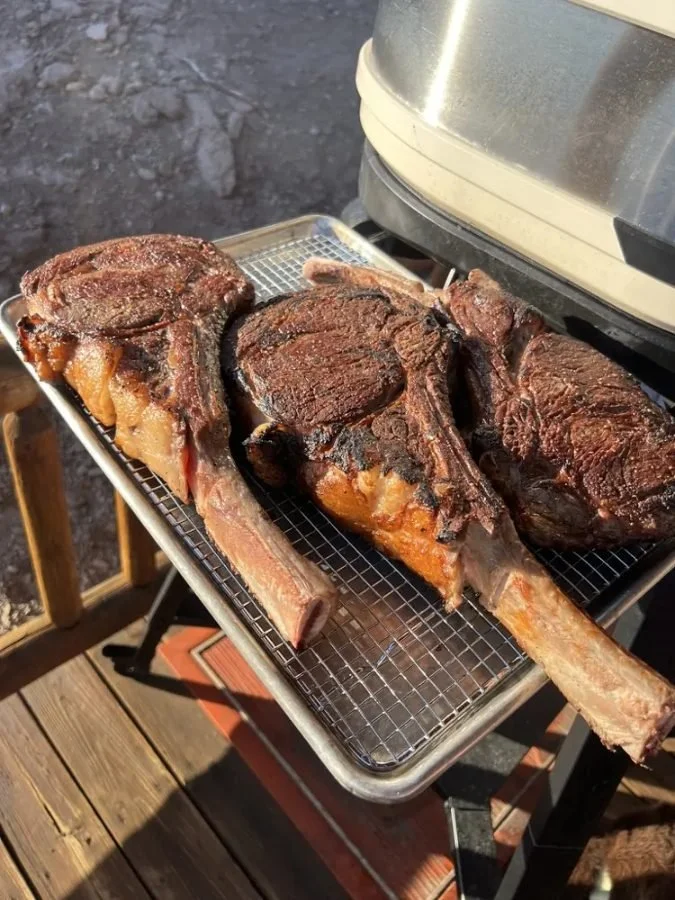 Tomahawk steaks resting beside the live-fire oven