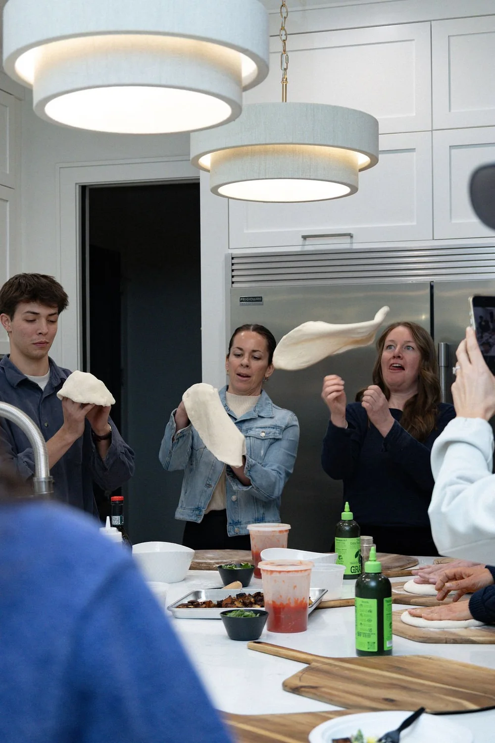 Students tossing pizza dough during a pizza class
