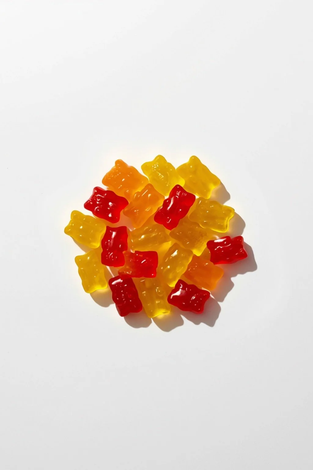 A pile of orange and red gummy bear candies on a light background
