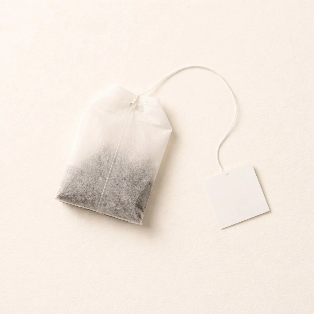 A single tea bag with a string and tag on a light background