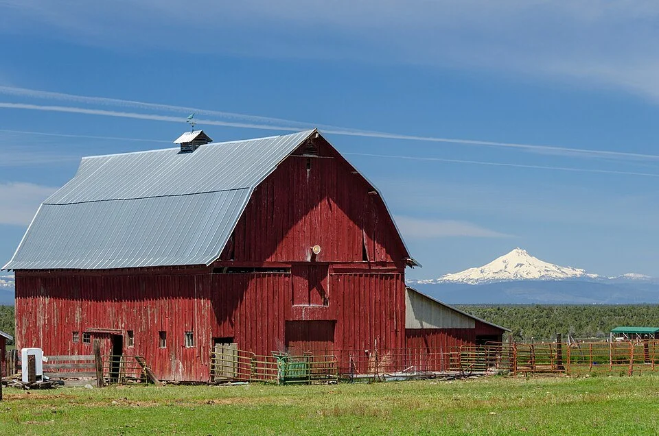 Central Oregon acreage landscape with a red barn on Powell Butte Road and a Cascade mountain beyond.