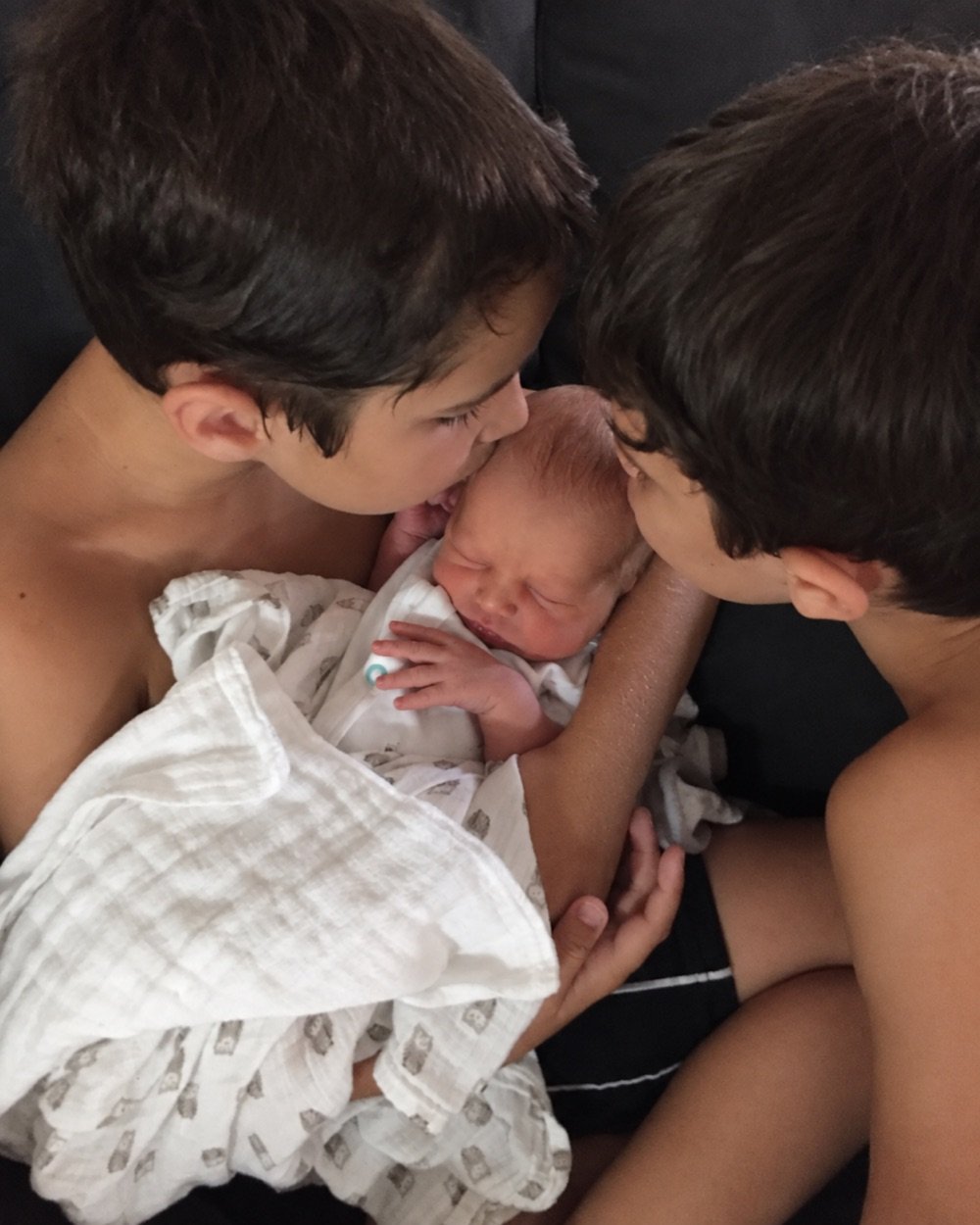 Shelise Murray’s two older sons kiss their newborn brother.