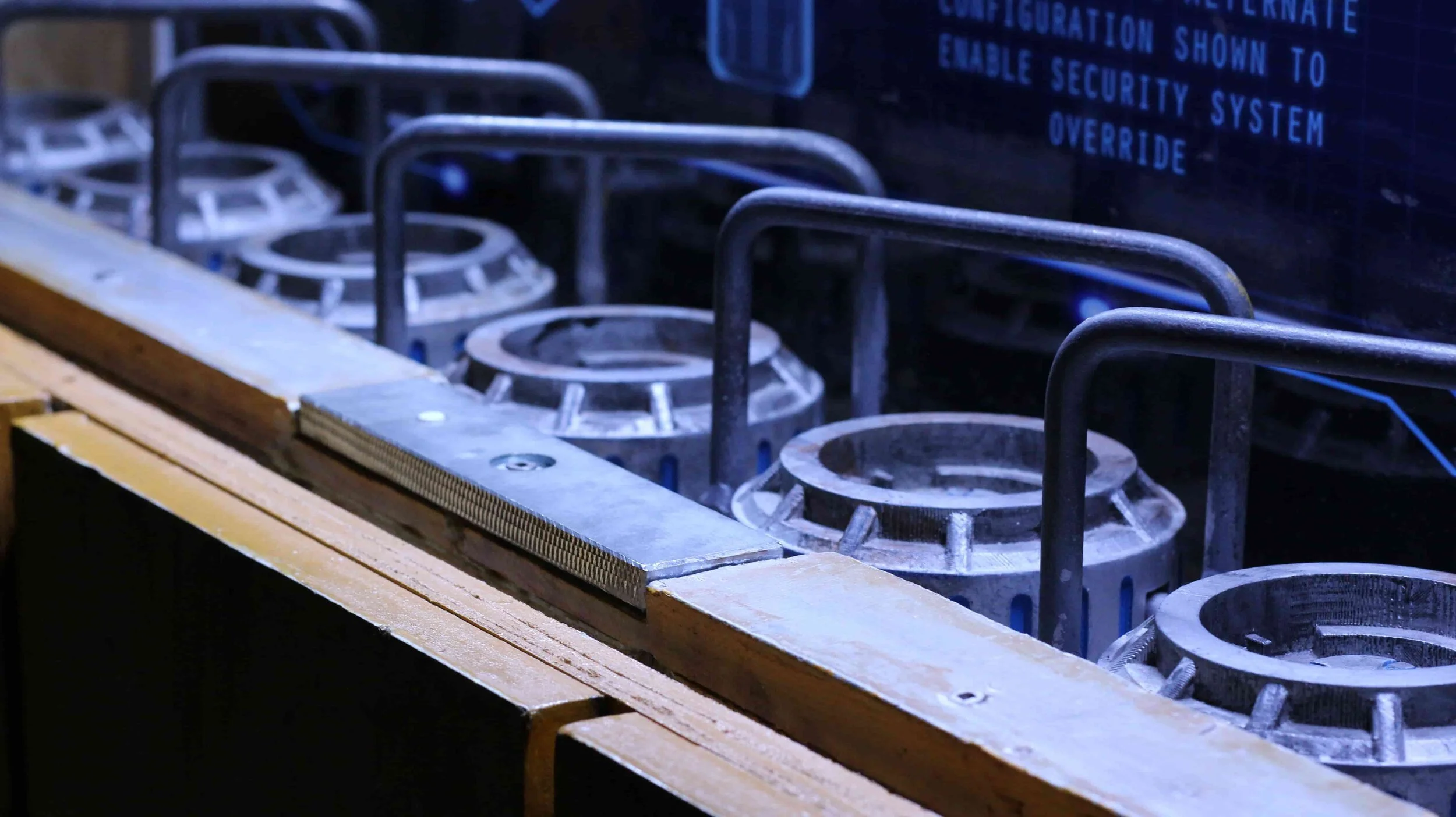 Row of circular vents behind metal rails beneath a glass panel with technical text.