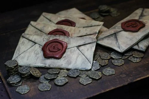 Wax-sealed envelopes and scattered coins arranged on a wooden tabletop.