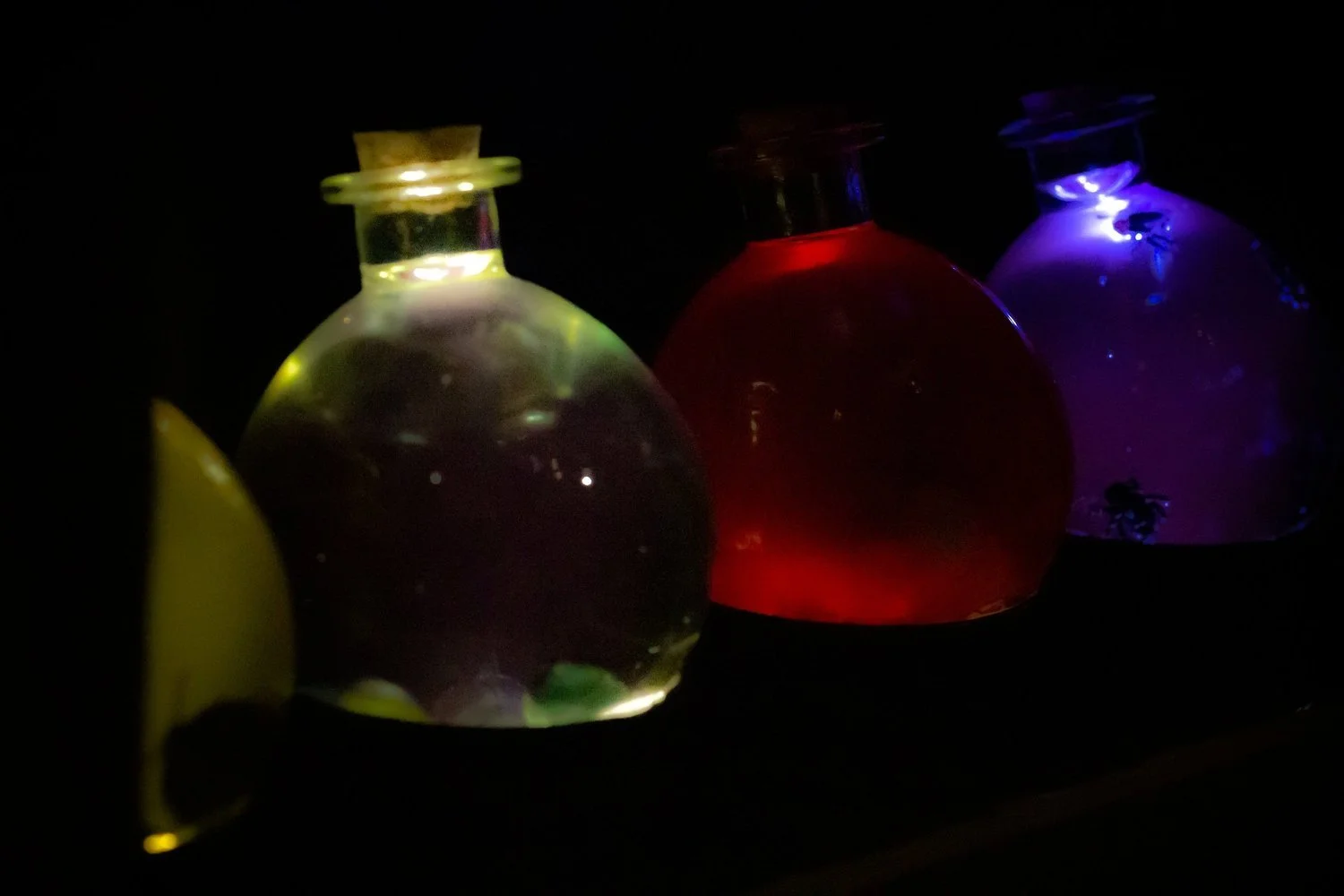 Shelves of glowing potion bottles and glass vials in a wizard's laboratory setting.