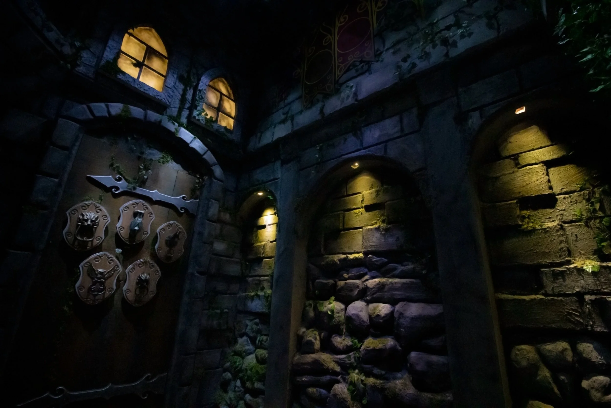 Medieval courtyard with arched stone niches and a shield-decorated wooden door.