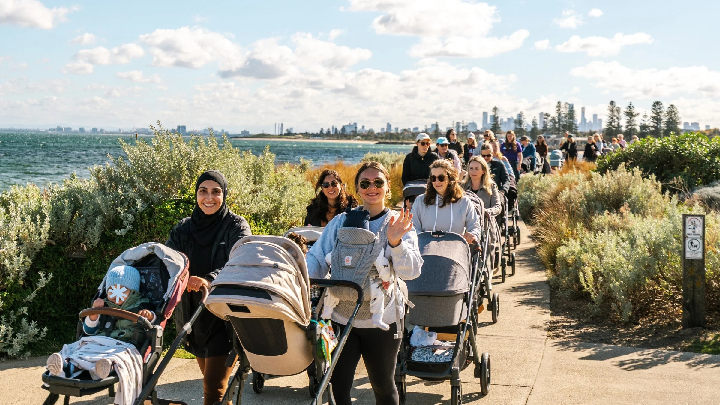 Three mums in No Mum Walks Alone tees smiling with their prams