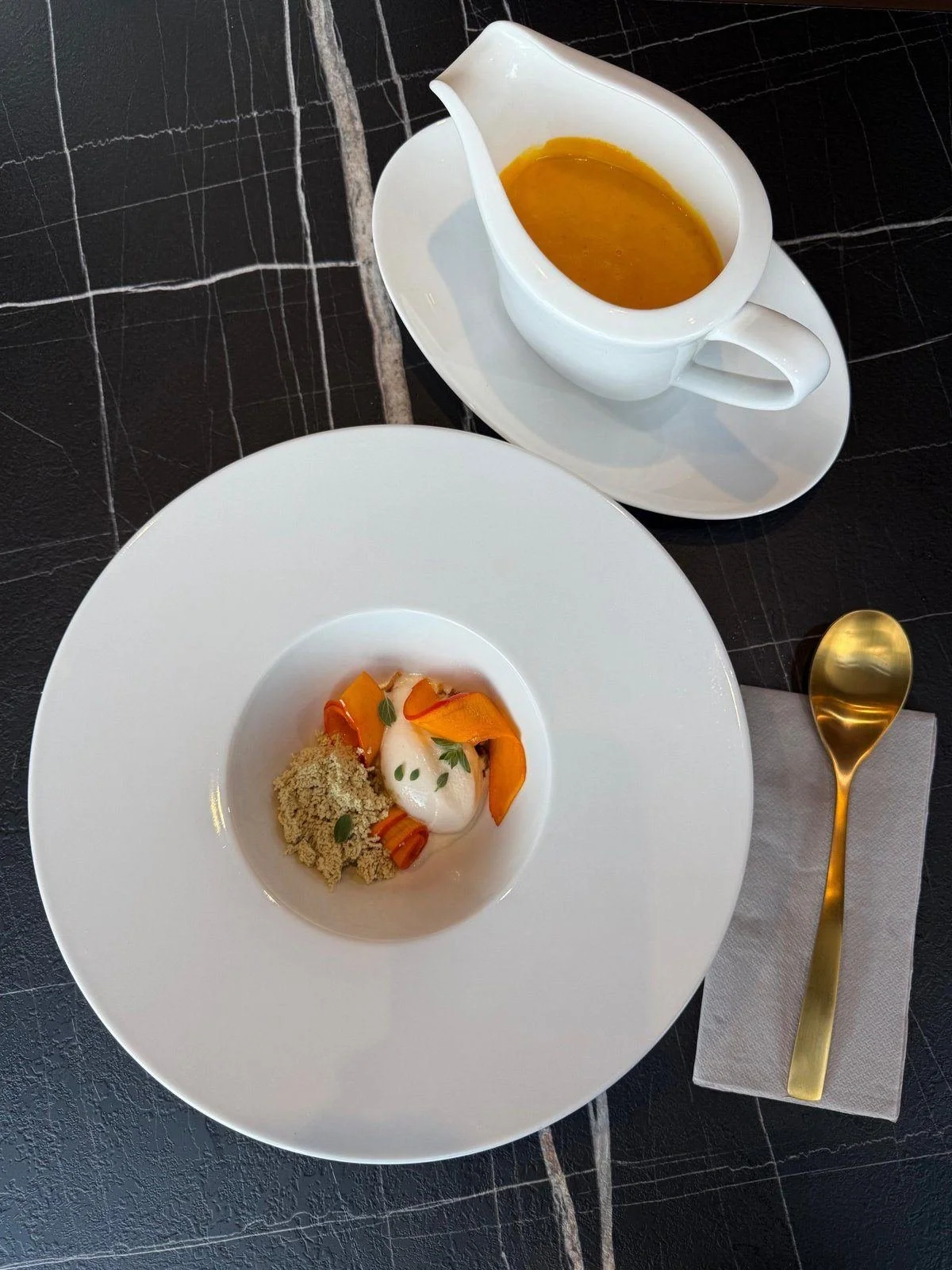 Gedeckter Platz im Bistro: Suppenteller, Sauciere mit Kürbissuppe und goldener Löffel