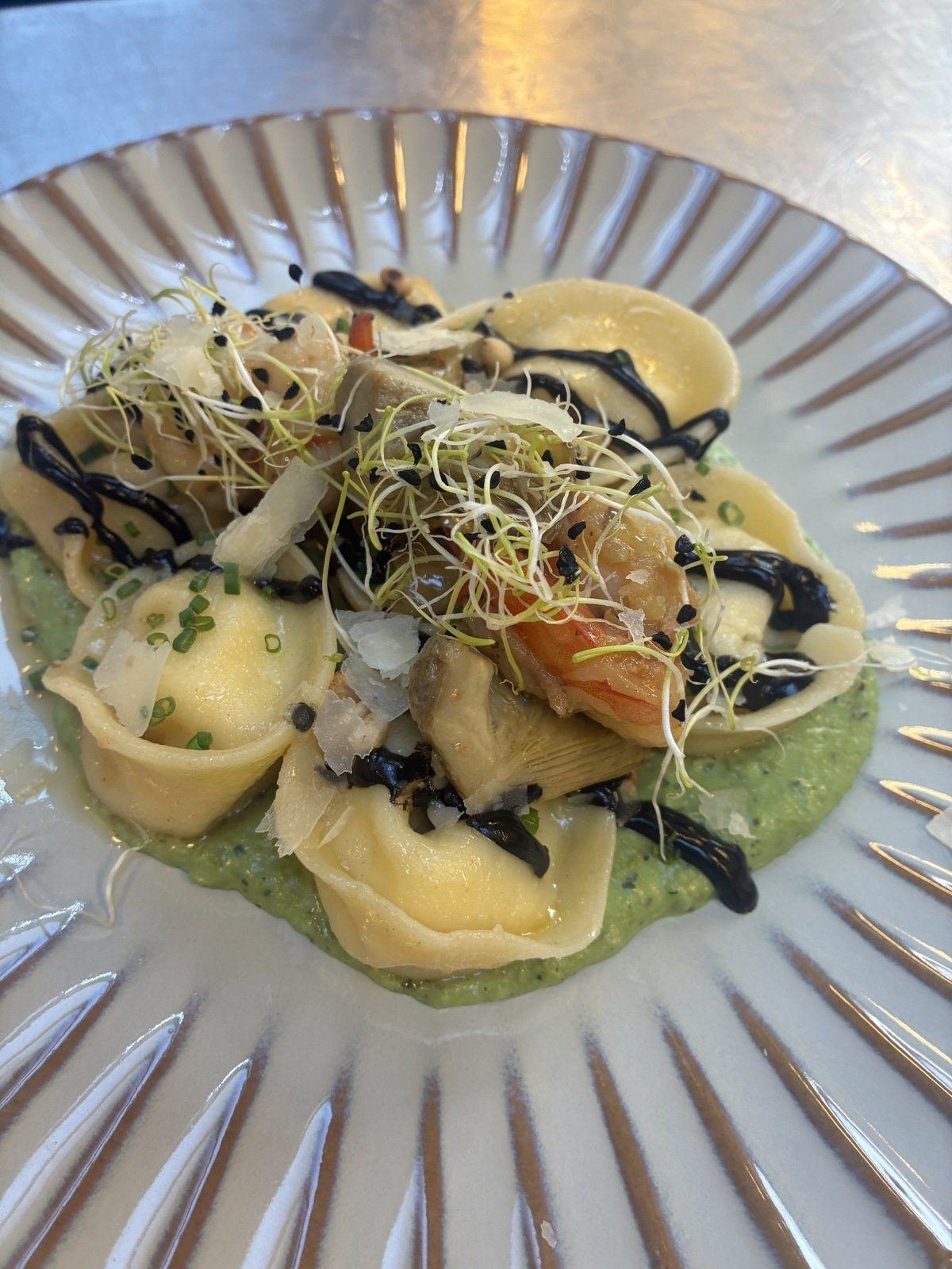 Hausgemachte Tortelloni mit Garnelen, Artischocken und Sprossen auf Erbsenpüree