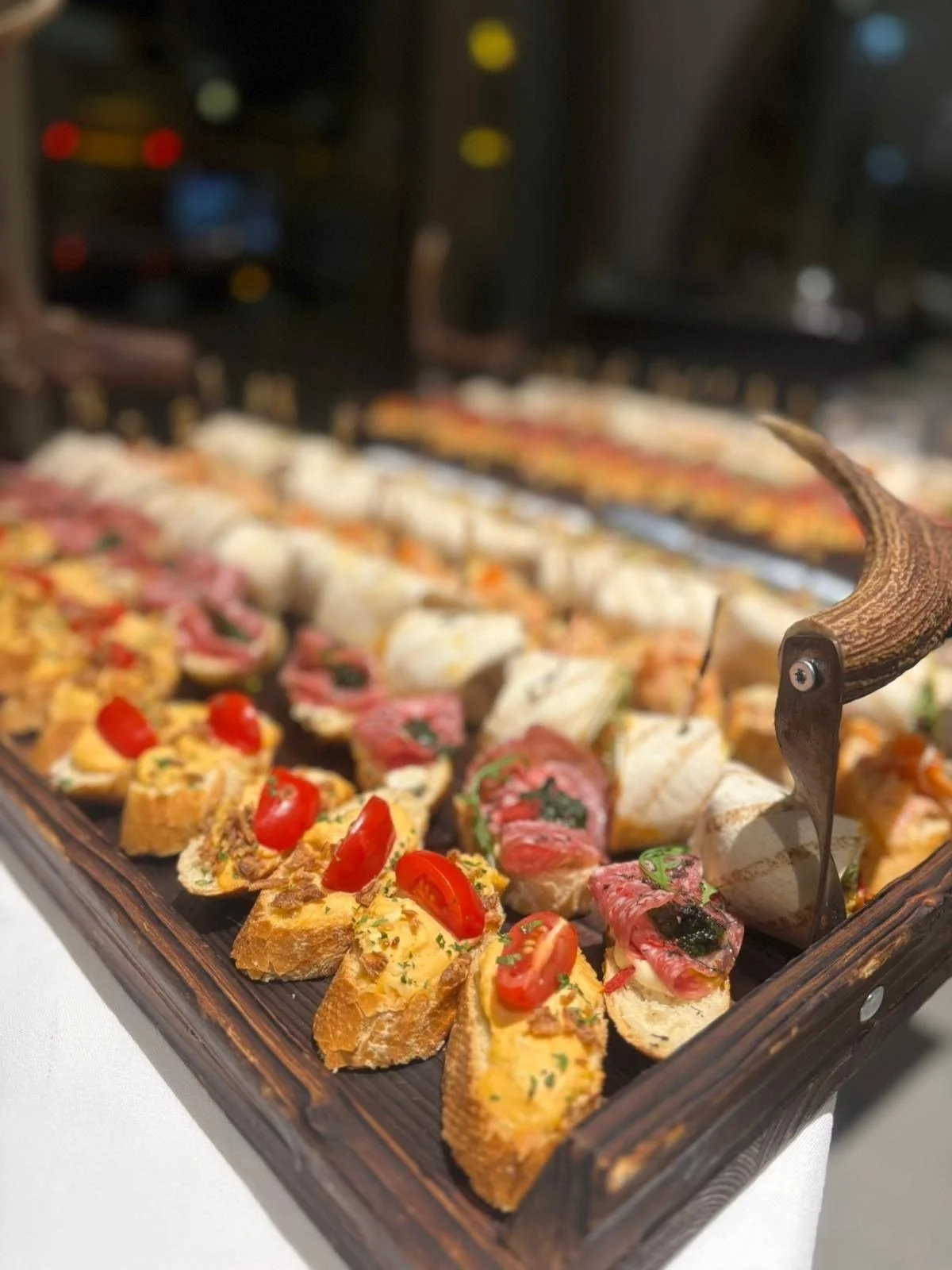 Holzbrett mit Geweihgriff voller Brötchen, Bruschette und Wraps beim Catering