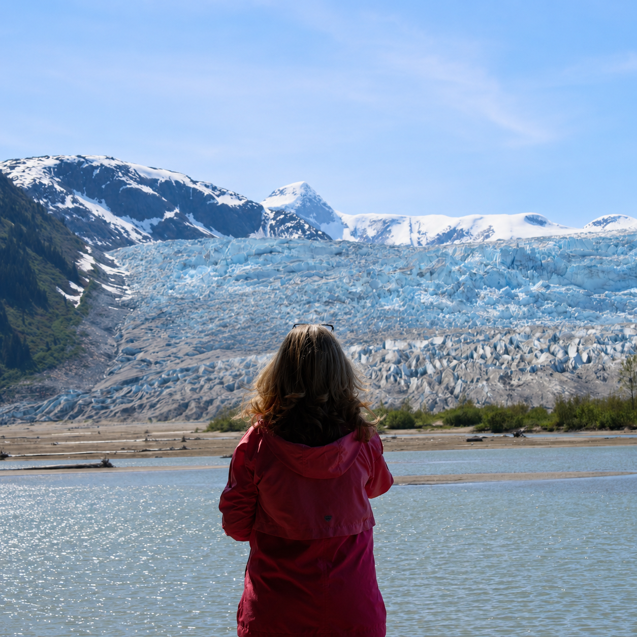 A woman taking in a glacier view from the scenic shoreline at Taku Glacier Lodge, Alaska