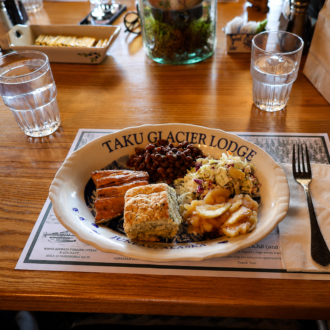 Plated Alaska salmon bake meal at Taku Glacier Lodge with coleslaw, beans, and herb biscuit