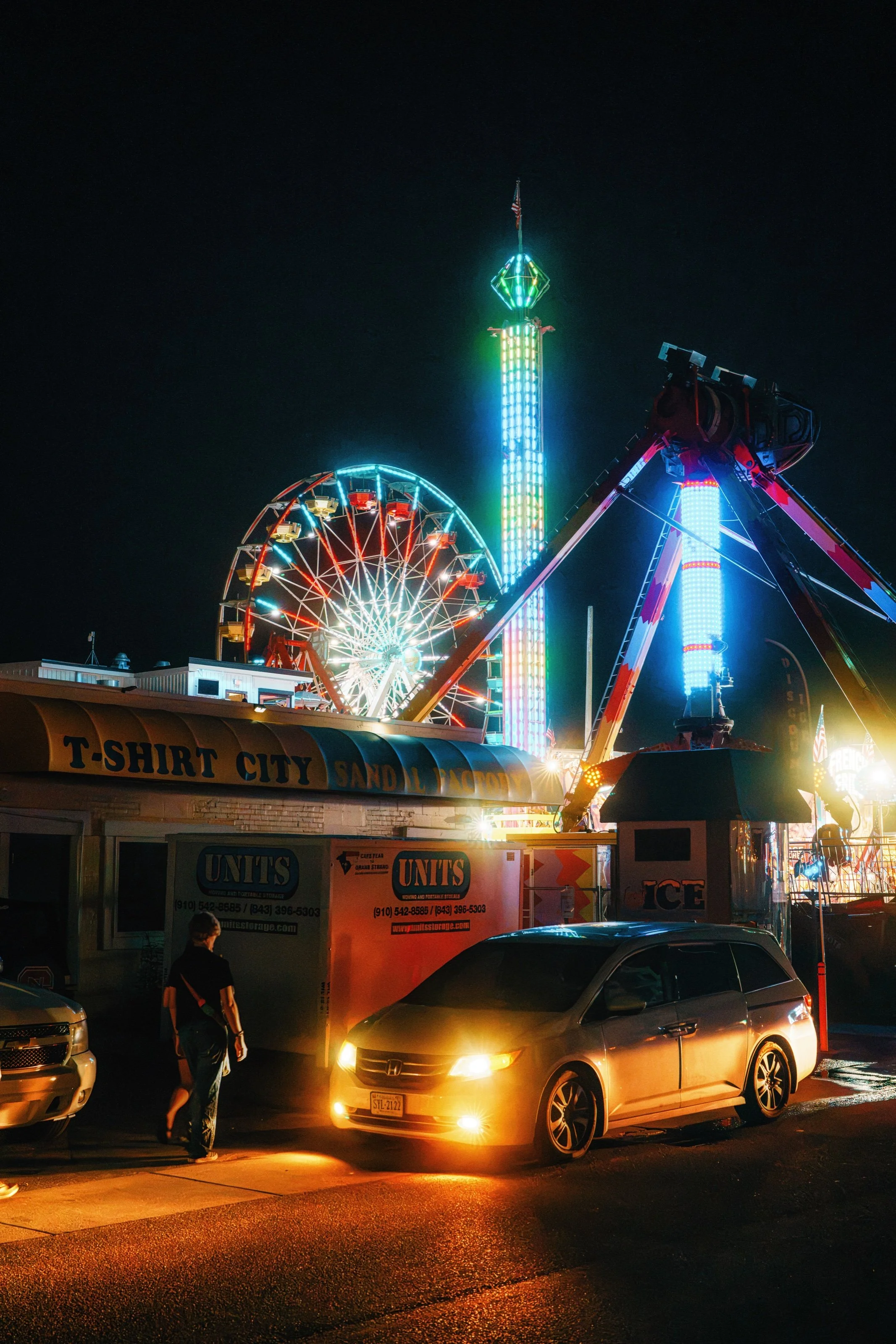 Neon-lit rides and traffic at the boardwalk at night