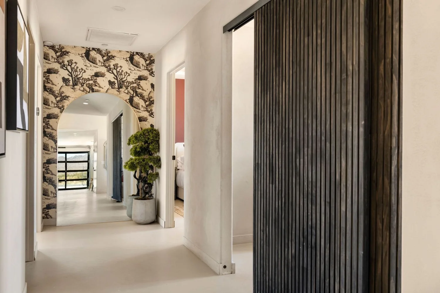 Arched hallway mirror and olive tree inside The Desert Willow Joshua Tree