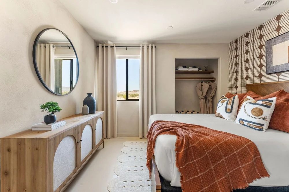 Dresser and round mirror beside a mountain-view window