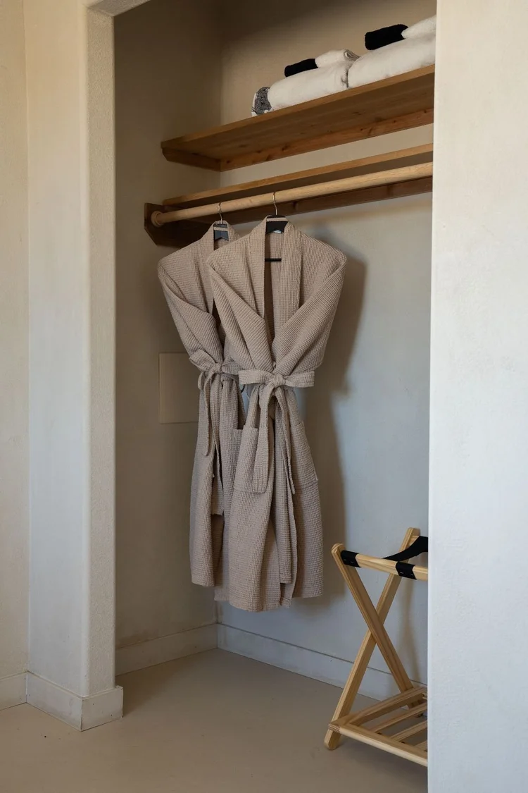 Fresh bathrobes and a luggage rack in the primary closet