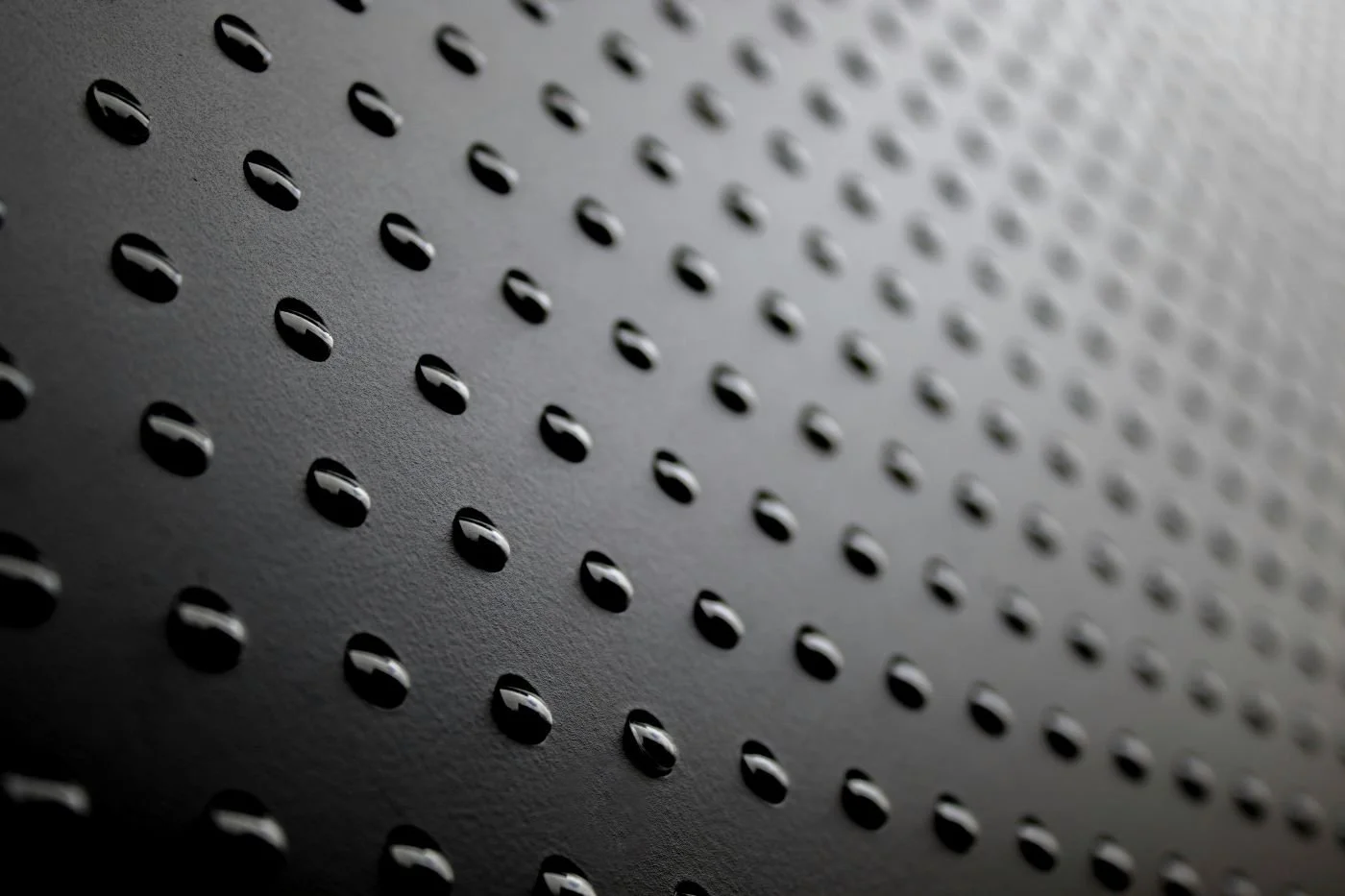 Perforated matte black metal surface — micro-abrasion finish reference