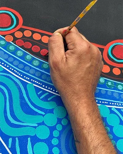 Close-up of a hand painting indigenous artwork for Mardaa