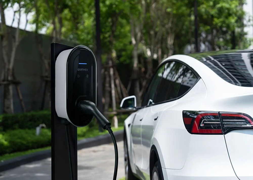 An Earth EV charging station next to a car