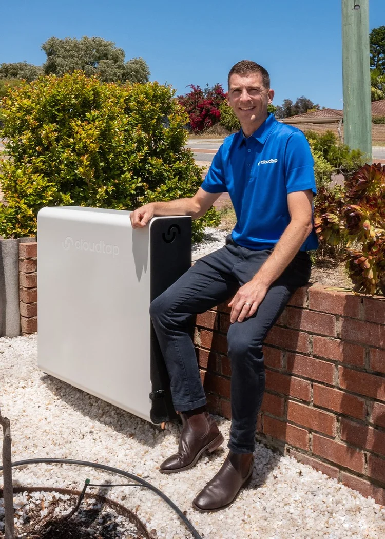 Cloudtap employee posing next to an installed Cloudtap unit