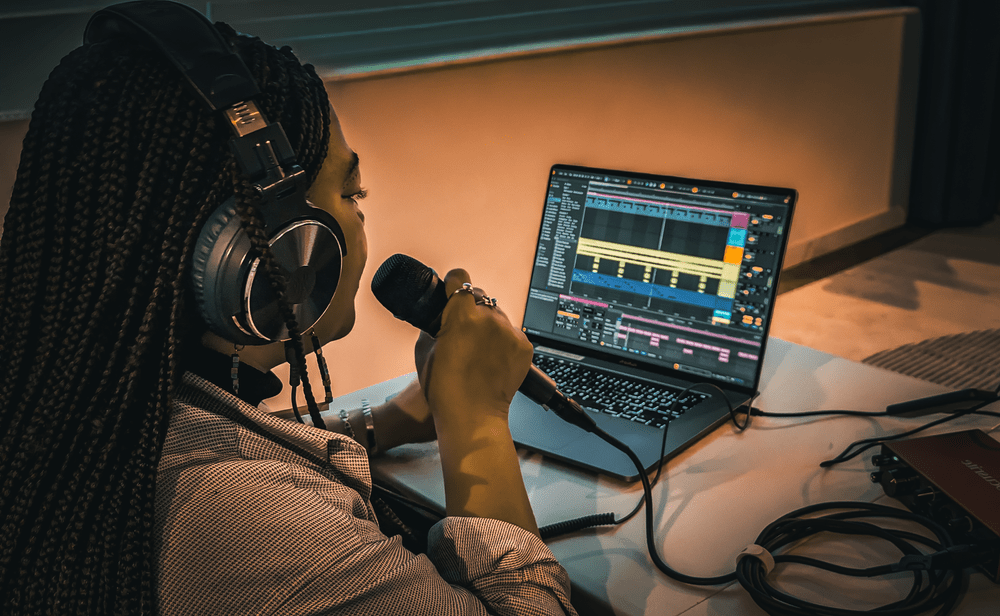 A student recording vocals into a microphone with Ableton Live open