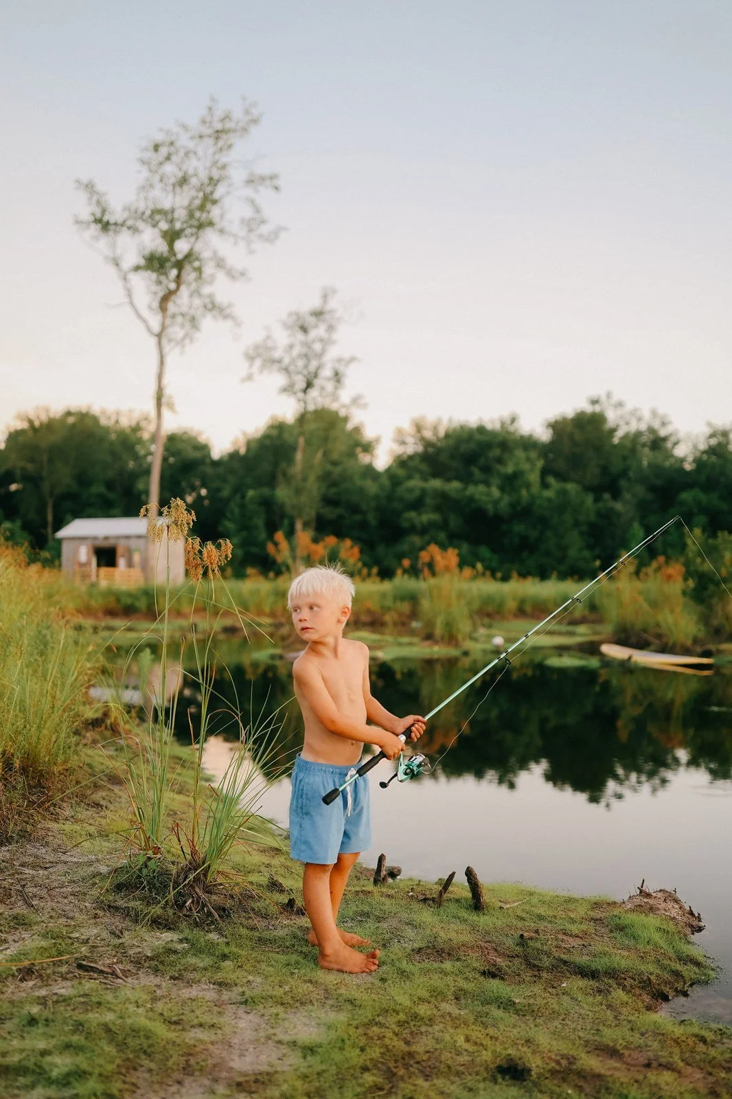 A child fishing beside the farm pond