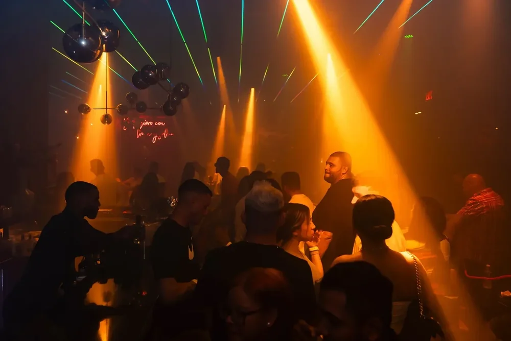 Crowd under orange spotlights and lasers on the Unico dance floor