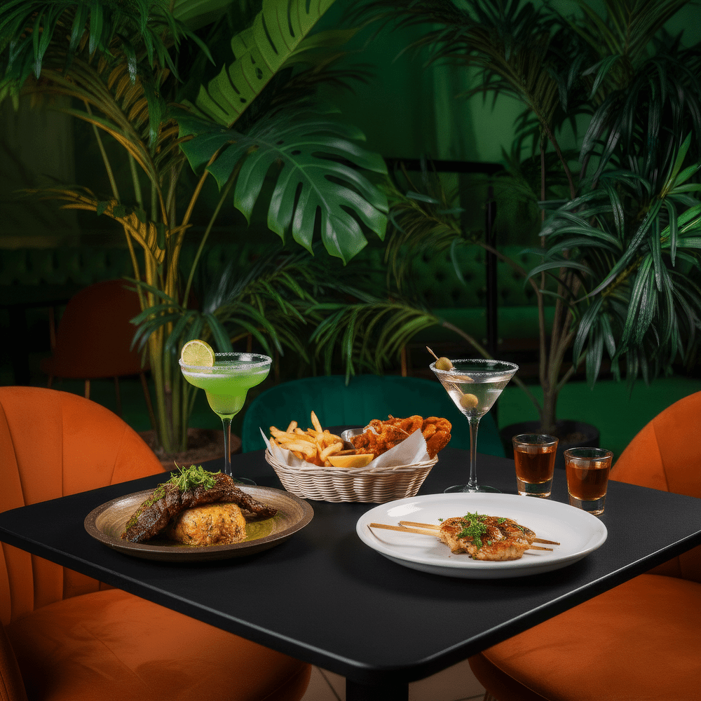 Skewers, a fried basket, steak and cocktails on a table surrounded by plants