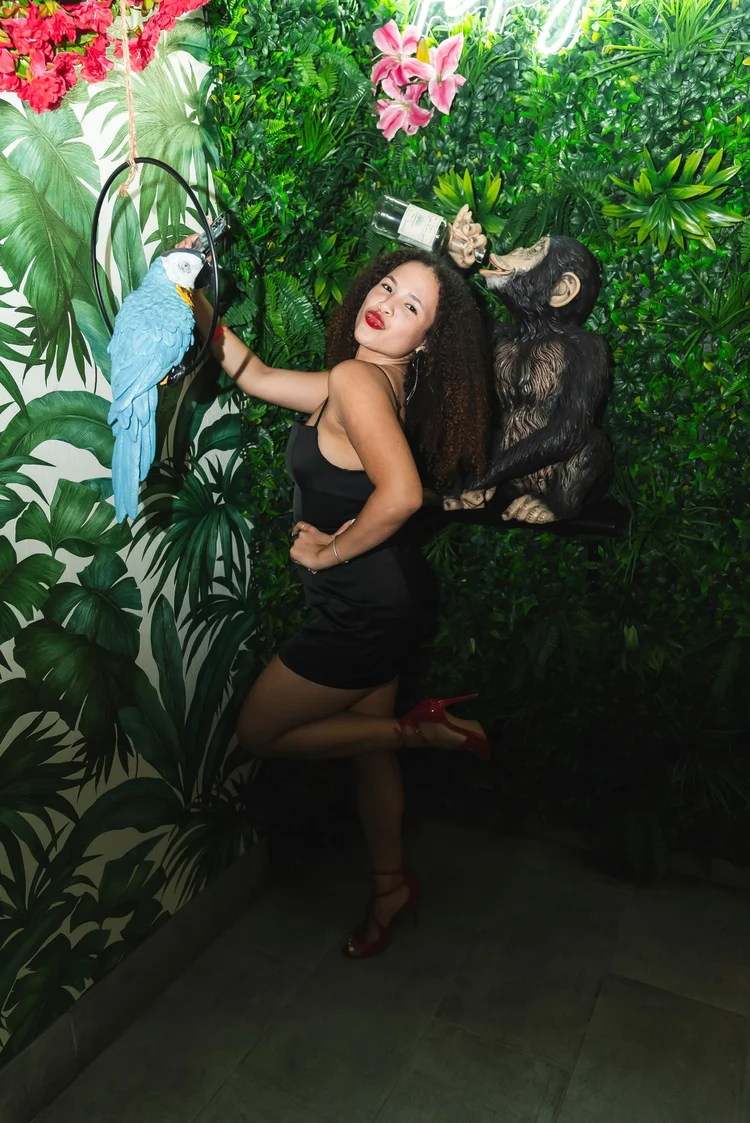 Guest posing at the jungle wall with the parrot and monkey statues