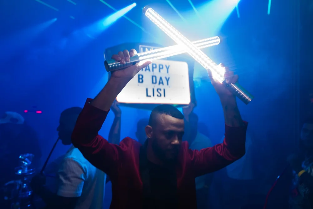 Guest holding up a Happy Birthday sign with sparklers under blue light