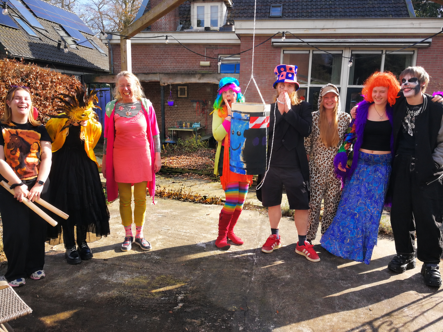 Jongeren en begeleiders in kleurrijke verkleedkleren op de patio van de Ponderosa