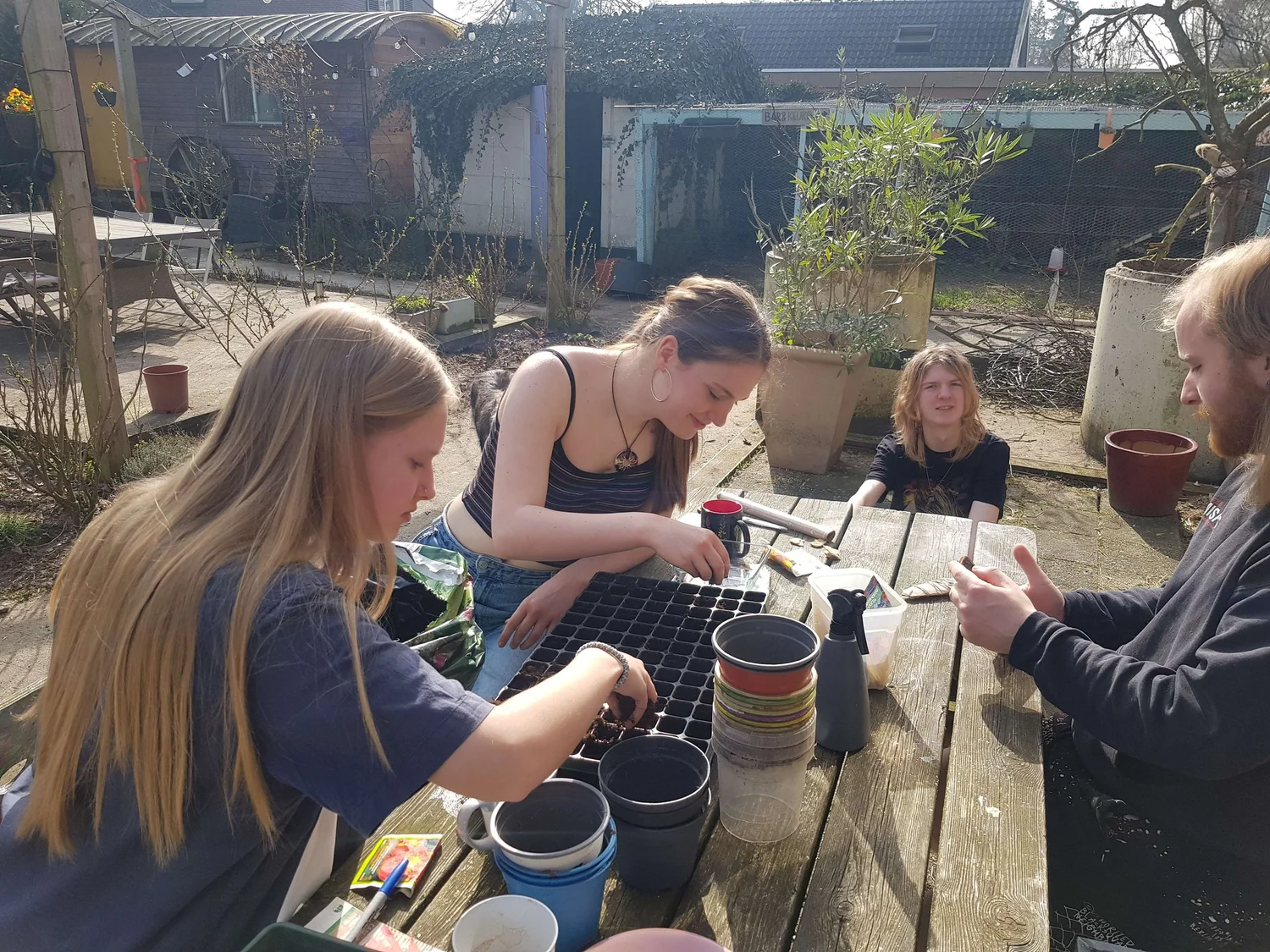 Jongeren zaaien en verpotten plantjes in de tuin van de Ponderosa