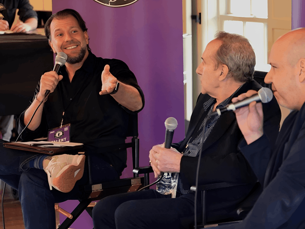 Three men having a discussion with microphones on a stage
