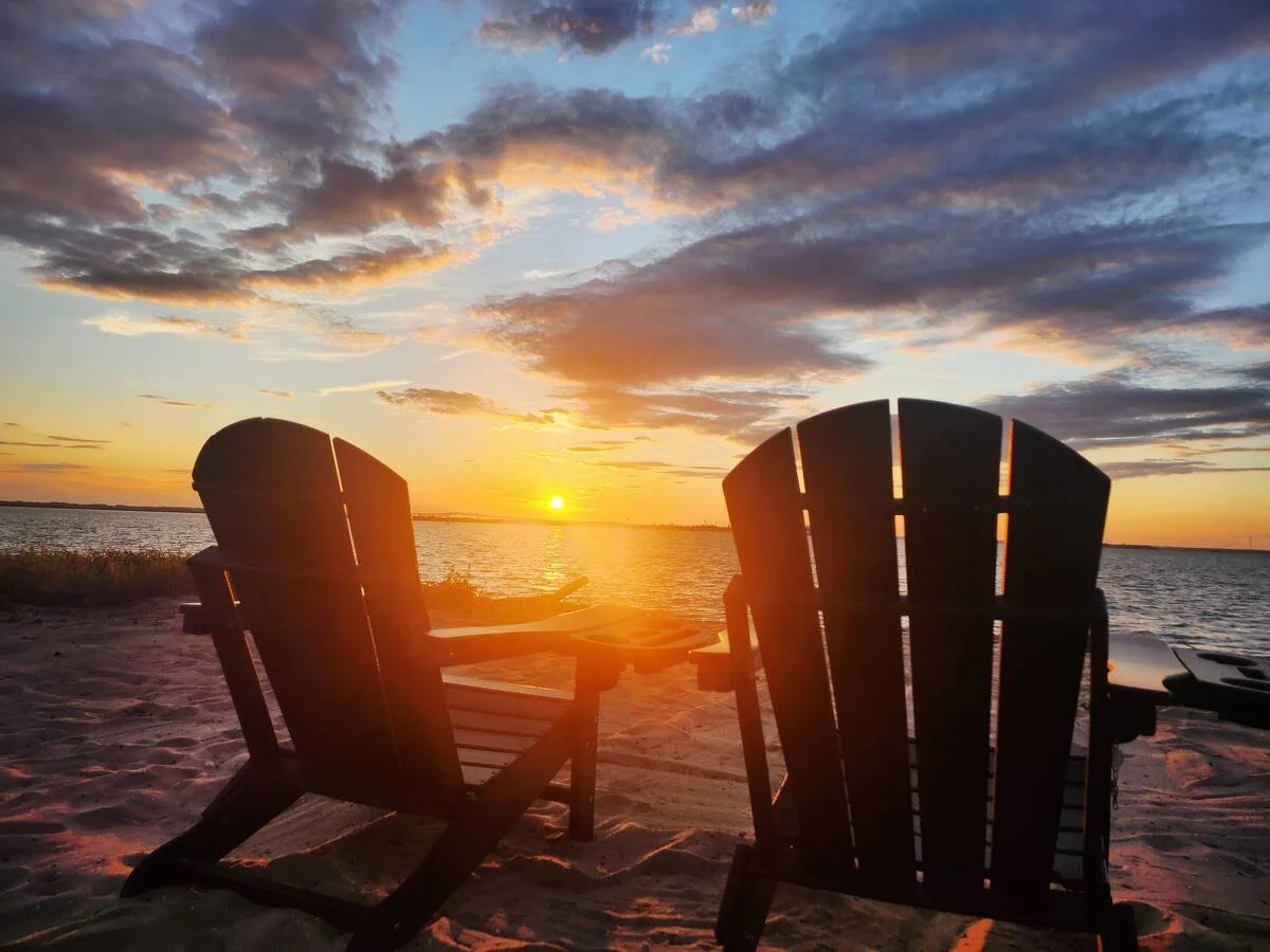 Sunset over the river viewed from two Adirondack chairs