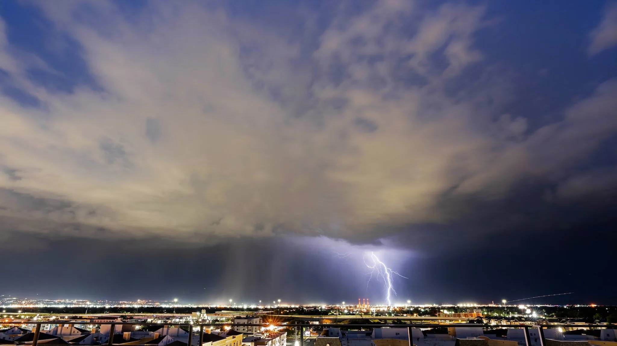 Lightning beneath storm clouds over a city at night
