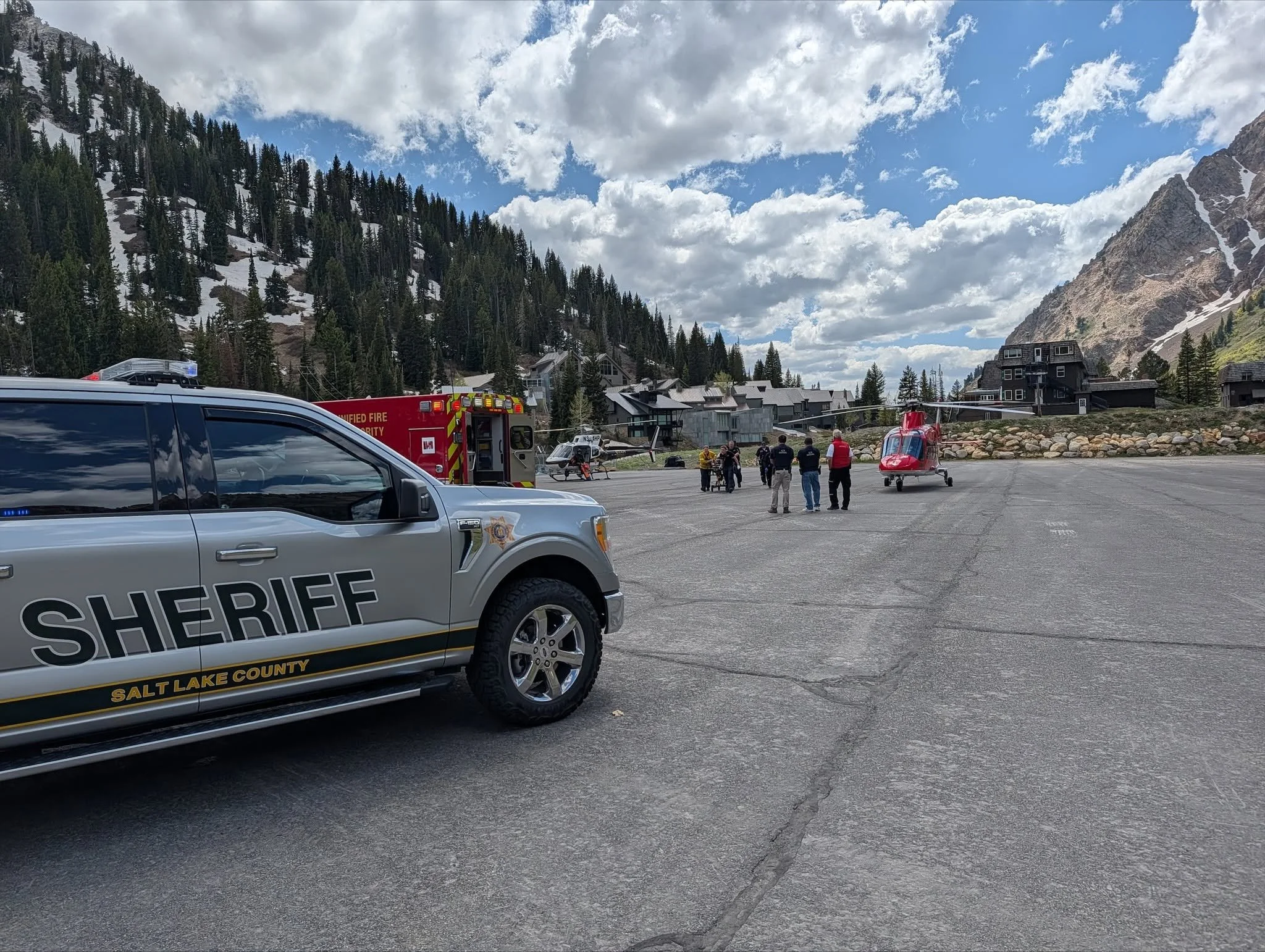 Search and rescue personnel, a sheriff vehicle and a helicopter at a mountain patient-transfer site