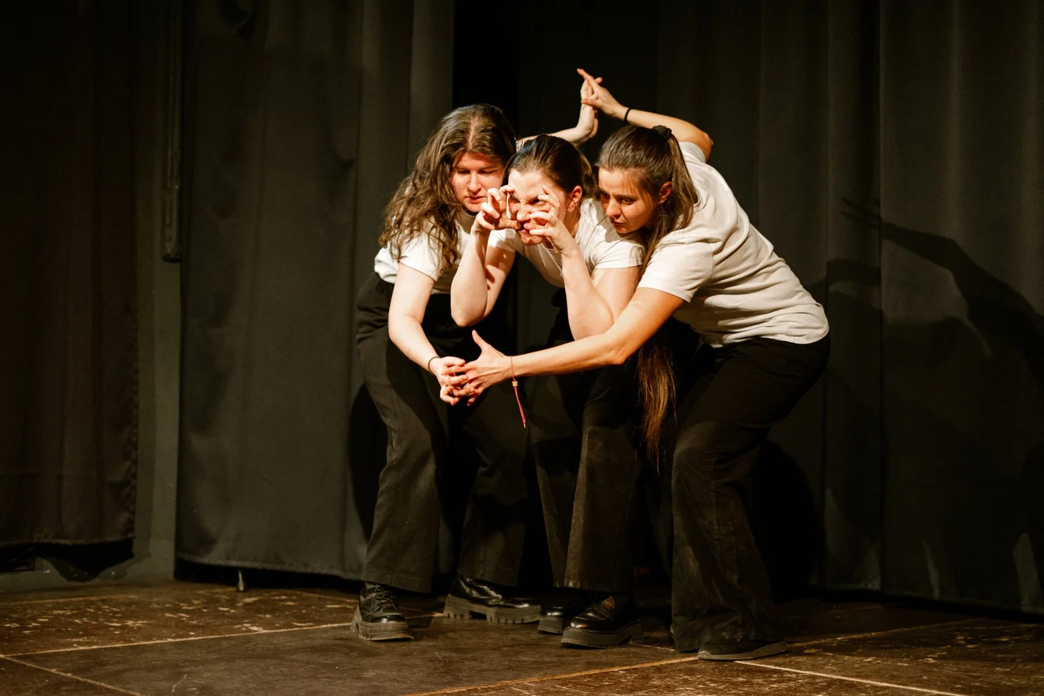 Three improvisers crouched together on stage, Extravaganza 1
