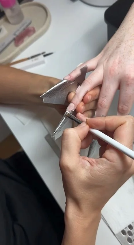 Elena Molodykh applying gel on paper forms during nail extensions training in New York