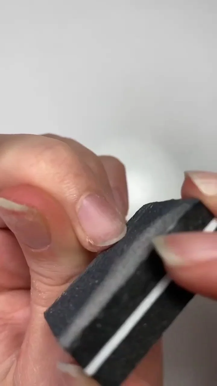 Lightly buffing the natural nail surface with a buffer block
