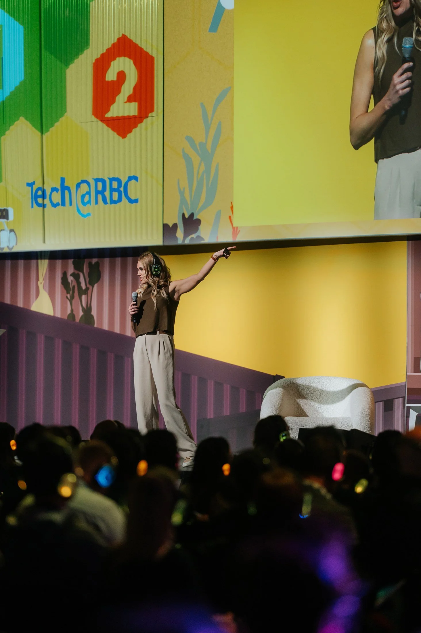 Rebecca Bultsma gesturing toward the stage screen at Upper Bound 2026.