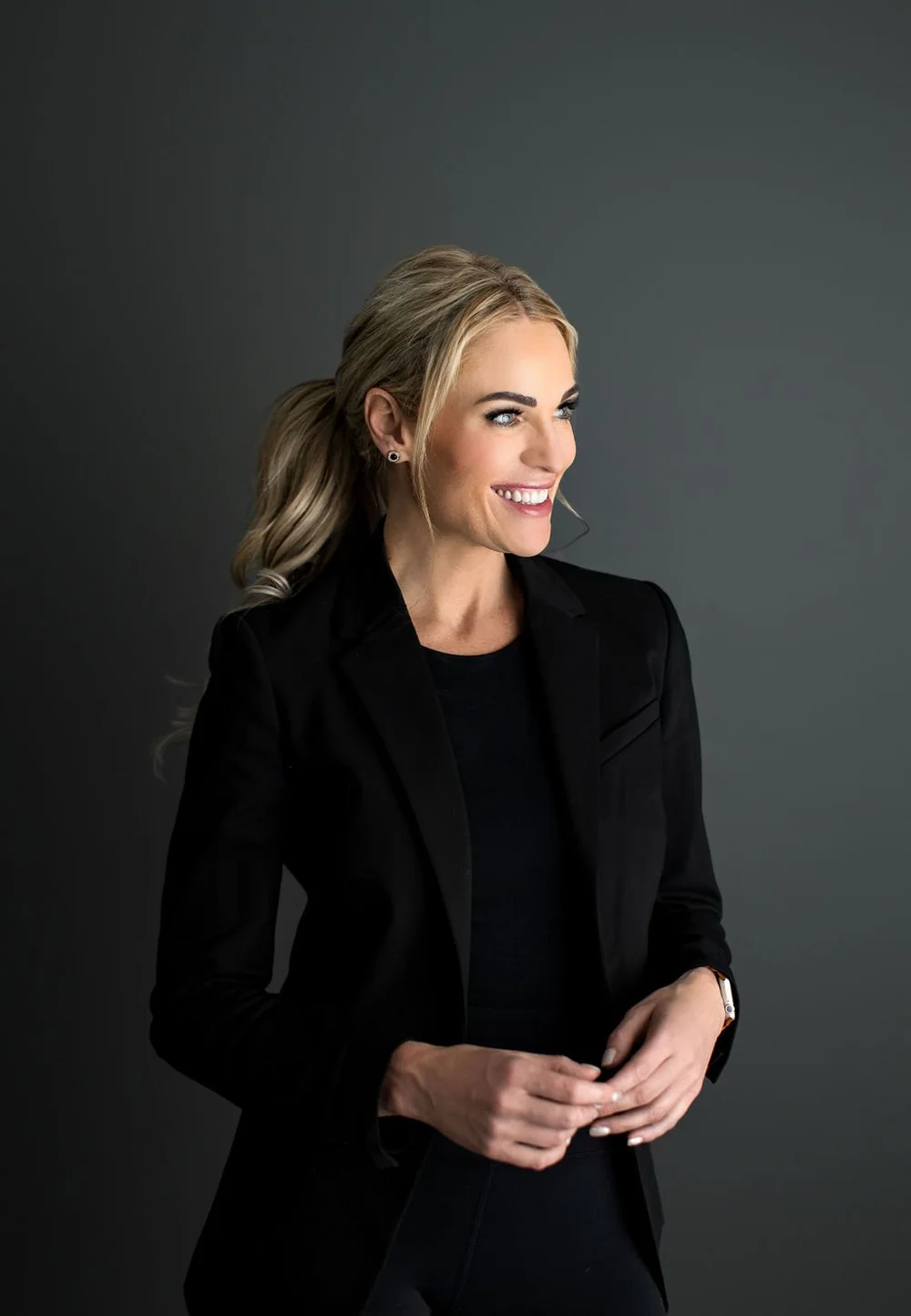 Rebecca Bultsma in a black jacket, smiling to the side with her blonde hair in a ponytail.
