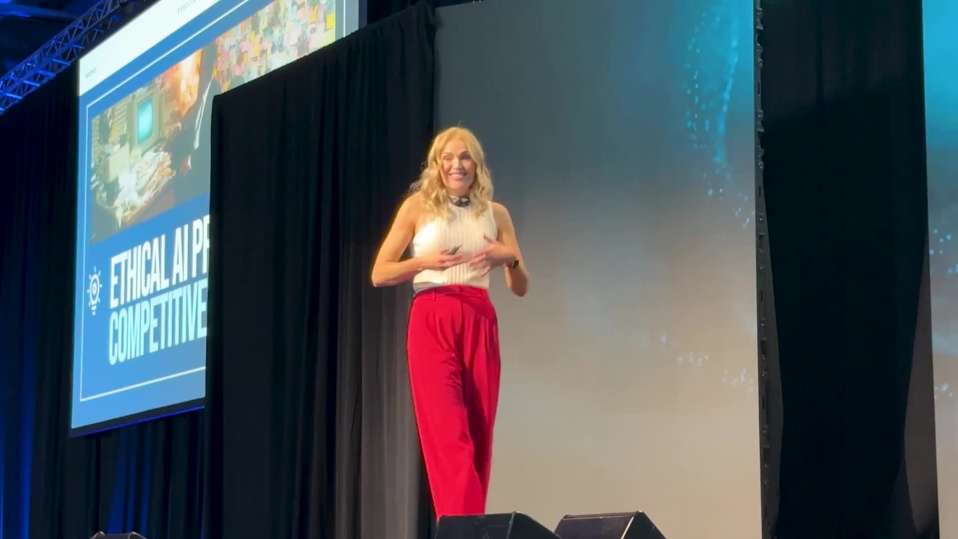 Rebecca Bultsma smiling toward the audience on stage at MAICON