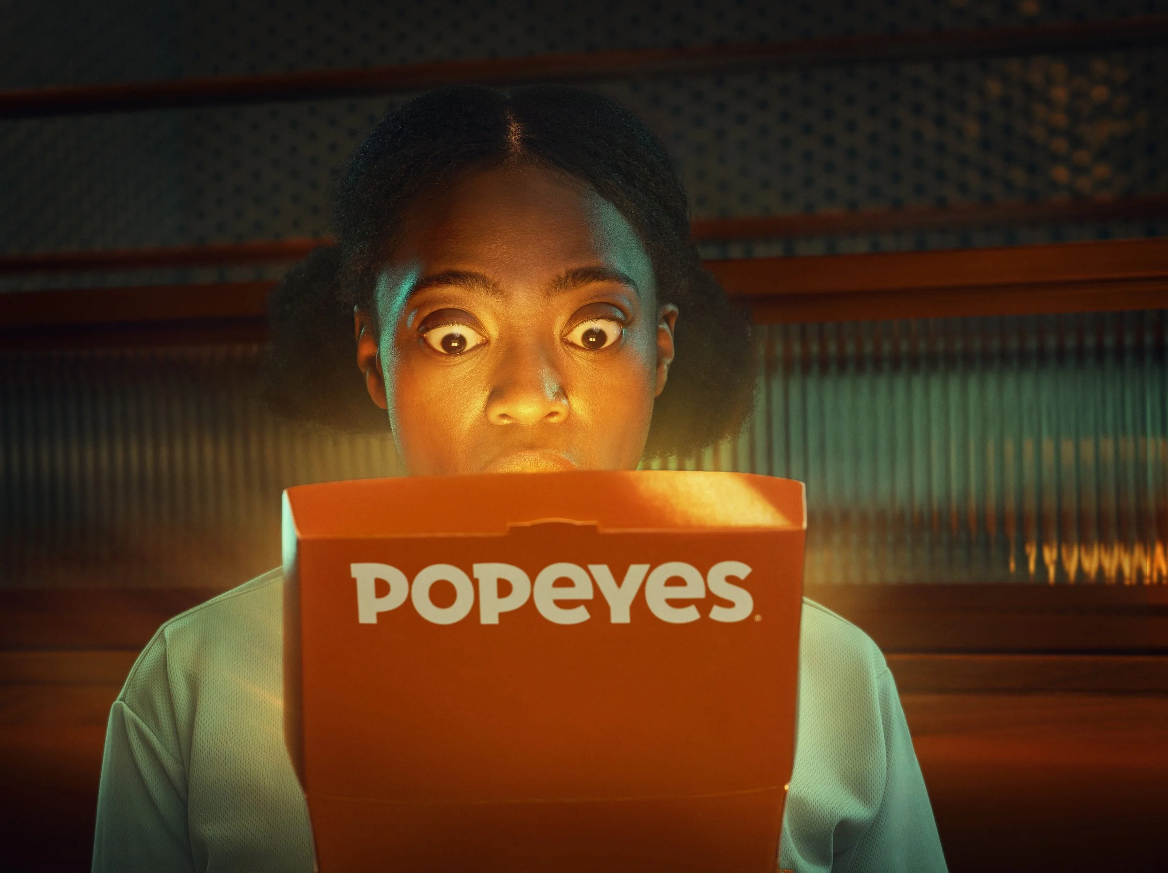Popeyes campaign portrait of a woman gazing into a glowing chicken box, photographed by Jon Enoch.
