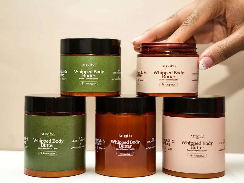 A hand lifting a jar of Amaria whipped body butter