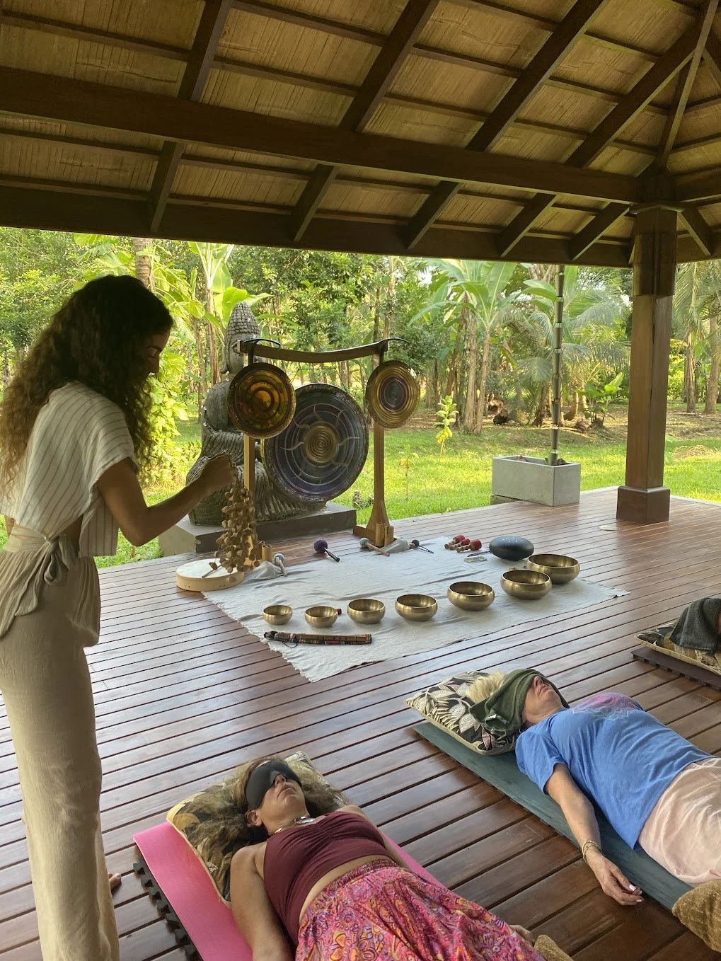 Yoselyn playing percussion beside two guests resting on a covered deck
