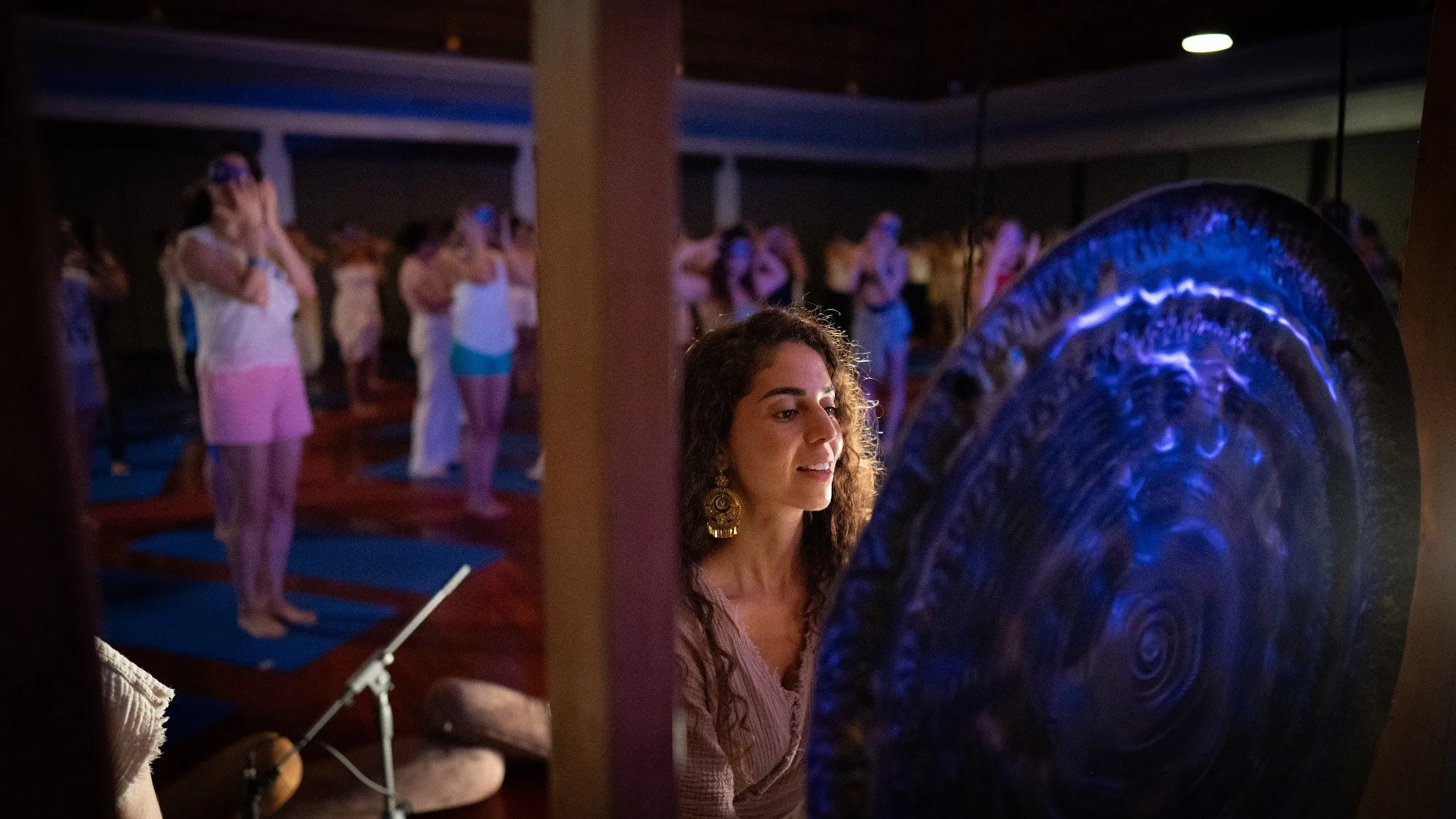 Yoselyn beside a large gong during a group retreat session