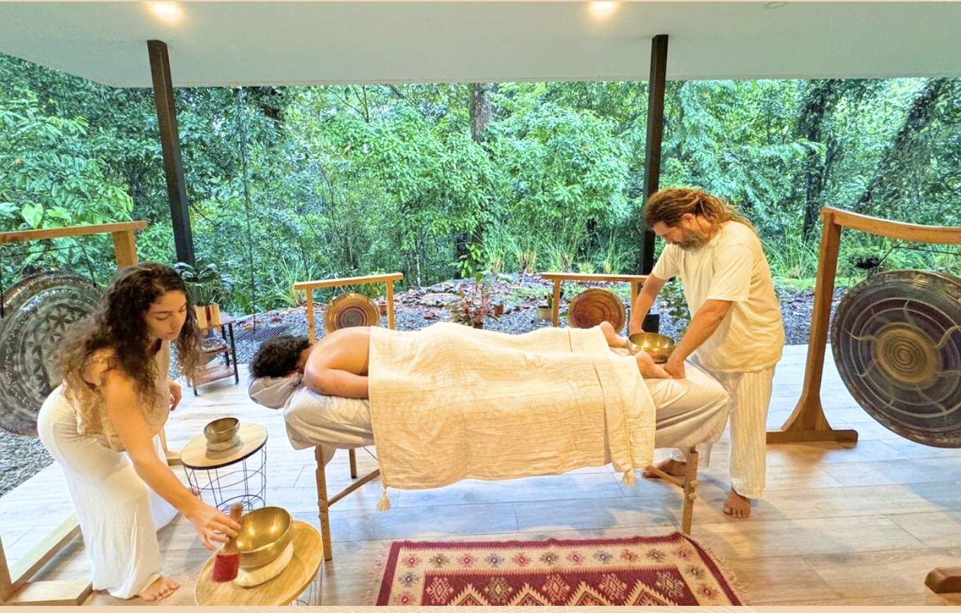 Lotus providing massage as Yoselyn plays a singing bowl beside the guest