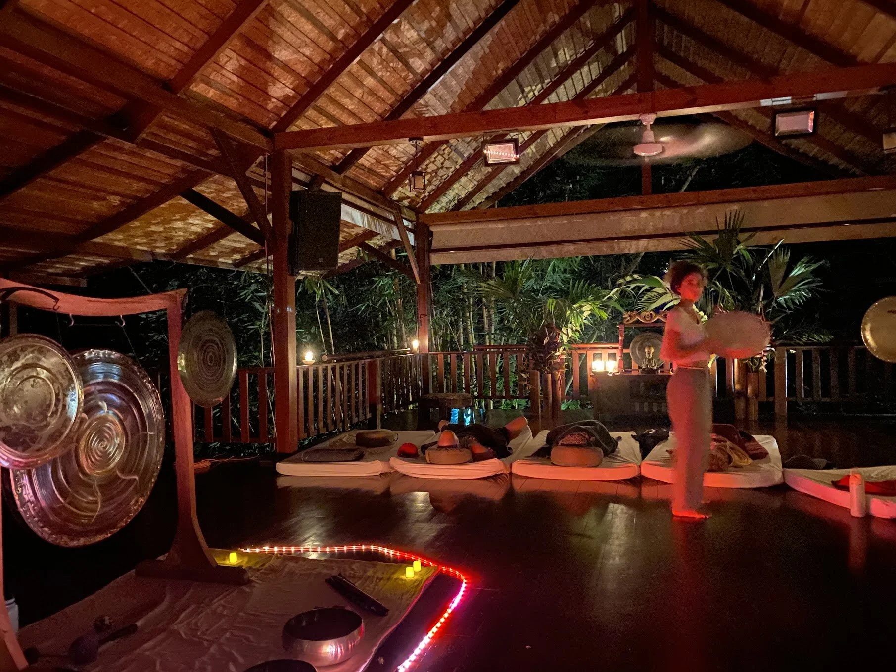 Evening sound journey with gongs, a frame drum and guests resting in a covered pavilion