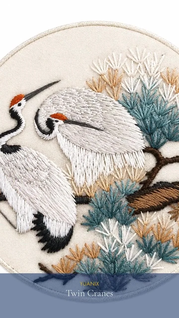A hand-embroidered blue bird on a branch of orange rowan berries